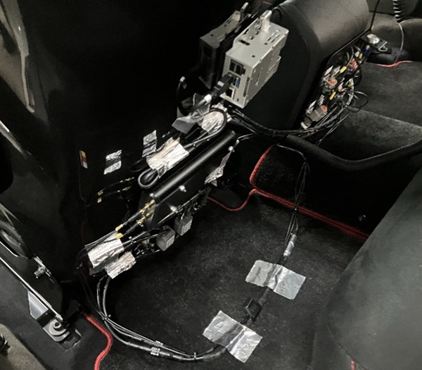 <写真:⾞両の中(前席シートバックに伝送端末を装着)>