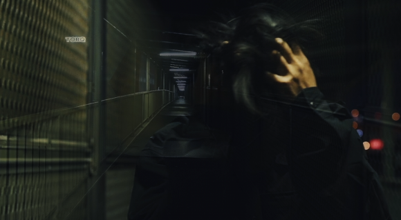 西成区の暗い通路を背景に、NISHIOKAの「ISHIKORO」のティザービデオの一場面。写真クレジット大島潤