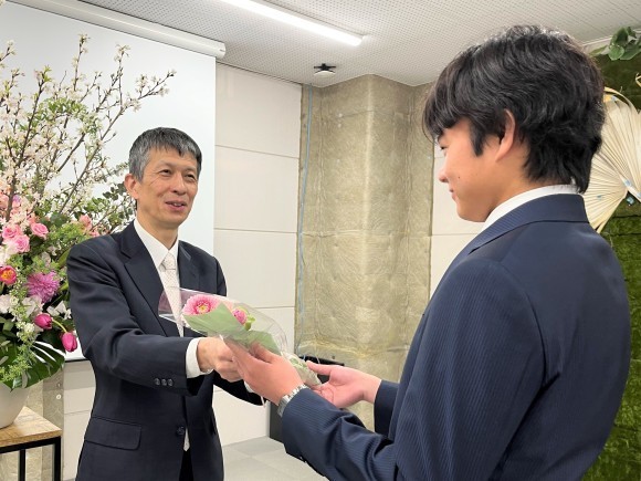 入社式で「希望」「常に前進」の花言葉をもつガーベラを手渡す様子　
