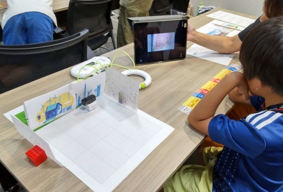 ワークショップの様子。プログラムしたロボットが絵を描いて作ったまちをカメラで移しながら走行する