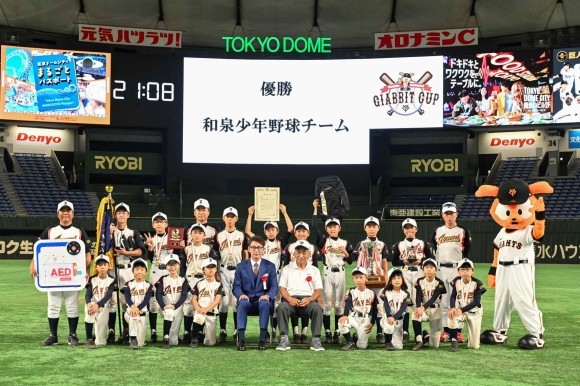 当社製AEDの目録と優勝した和泉少年野球チームの皆さん、ジャイアンツアカデミー校長 元木大介氏らと記念撮影