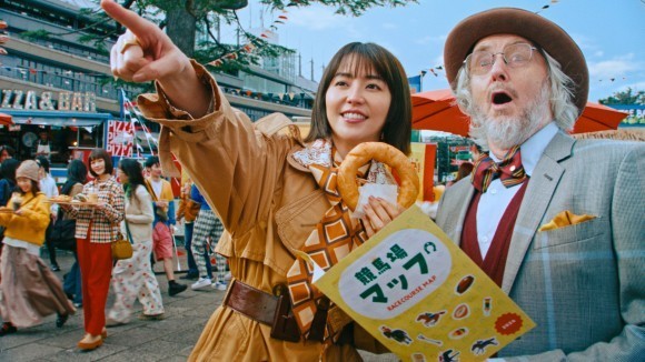 、大穴ドーナツを片手に流暢な英語で外国人に道案内をしている長澤さん